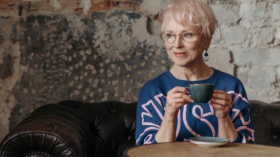 an elderly woman enjoys a cappucino at the cafe